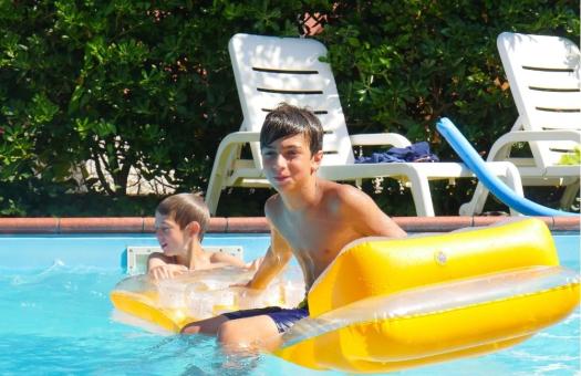 Deux garçons jouent dans la piscine avec un matelas jaune.