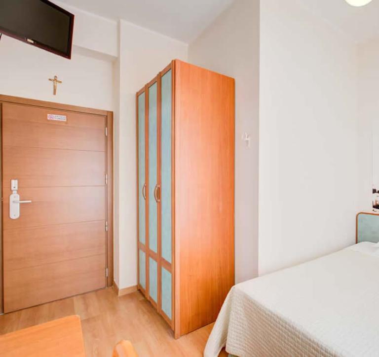 Zimmer mit Bett, Schrank, Fernseher und Biker-Poster.
